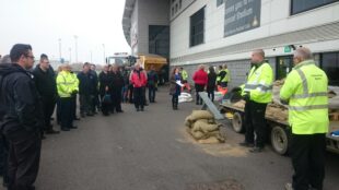 Our field team demonstrating how to build an effective sand bag wall