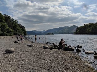 People sitting on the shores of Derwentwater during summer 2018
