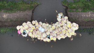 View from the air of large sandbags placed to block a breach in a river bank 