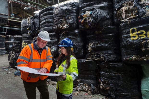 Two EA staff monitoring a waste site with waste bales in the background