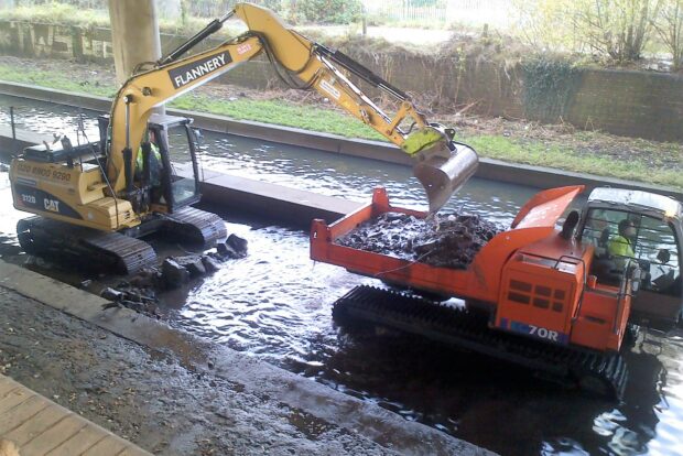 two vehicles dredging a river