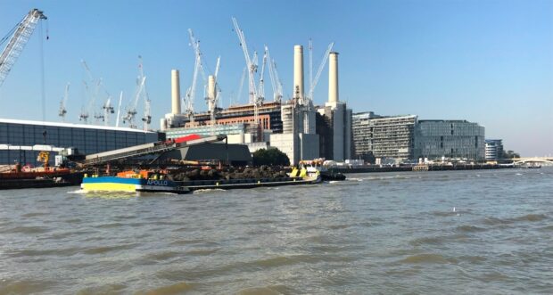 Former Battersea Power Station next to River Thames with river barge carrying spoil.