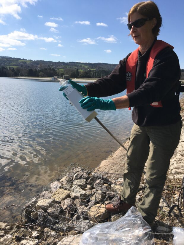 An Environment Agency officer filling sample bottles with water from Blagdon Water in Devon