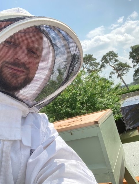 An Environment Agency officer in a bee keeping suit next to one of his bee hives.