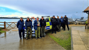 eight men stood in front of a police car in a mix of police and Environment Agency uniforms