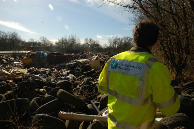 Environment Agency officer investigates a pile of illegally dumped waste