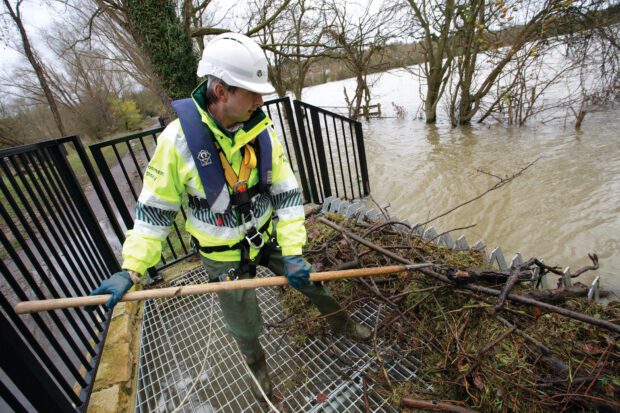 An EA employee clearing debris from a trash screen