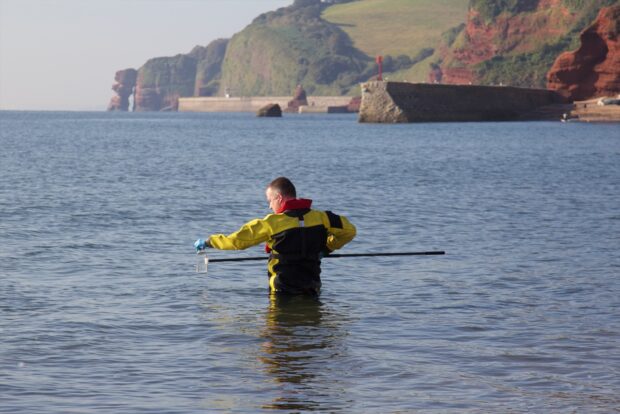 4. Environment Agency staff member in the sea taking a sample of the water.