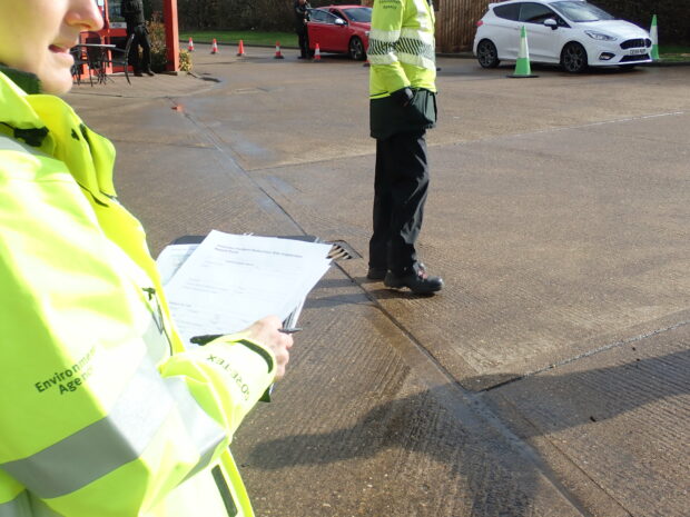 Officer holding an inspection checklist with another officer in the background in branded EA clothes.