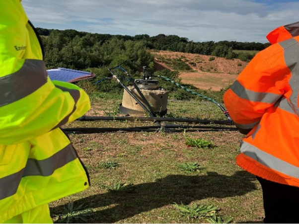 A capped landfill with monitoring equipment in a grassy area