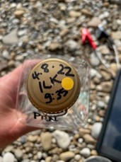 The image shows the lid of a water sampling bottle, which has the date, time and location written on it. This is one of the bathing water samples taken from the River Wharfe at Ilkley. 