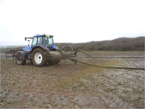 A tractor spreads slurry on a field. 