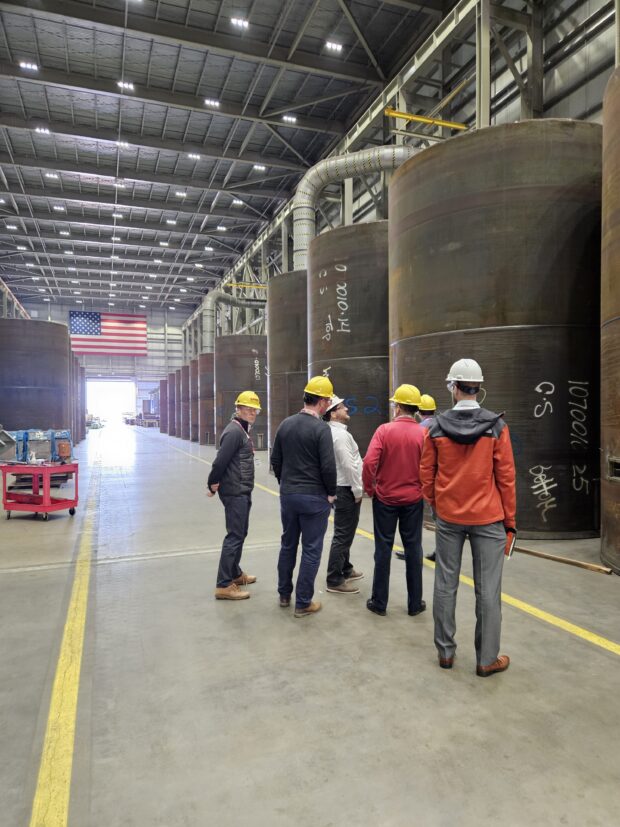 Group of people in hard hats and goggles in a nuclear storage cask manufacturing centre