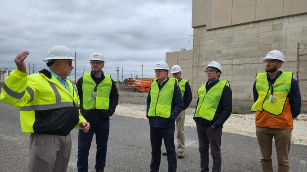 Group of people in protective gear standing outside a decommissioned nuclear facility