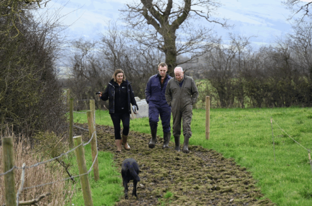 Environment Agency officer on a farm inspection. Walking through a field with 2 farmers. A dog can be seen at the front of the image