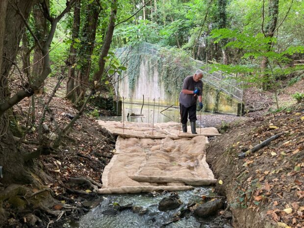 An Environment Agency officer installing sediment mats on the River Chelt to capture excess silt, which can be harmful to aquatic life