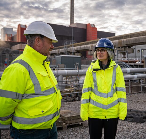 Two people wearing hi-vis jackets in front of Sellafield nuclear power station.