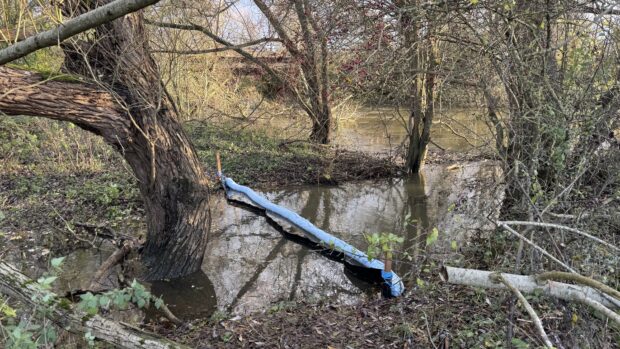 A tributary of the River Cherwell with a barrier in the water to prevent waste entering. 