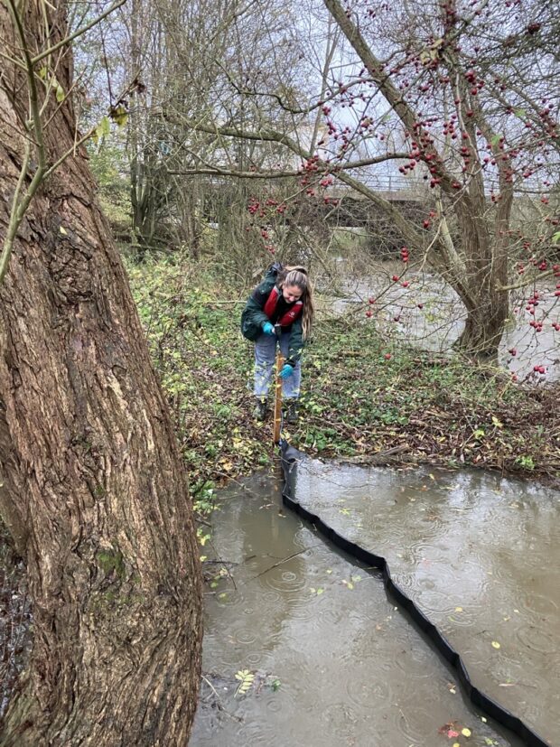 An absorbent boom being put into a tributary of the River Cherwell