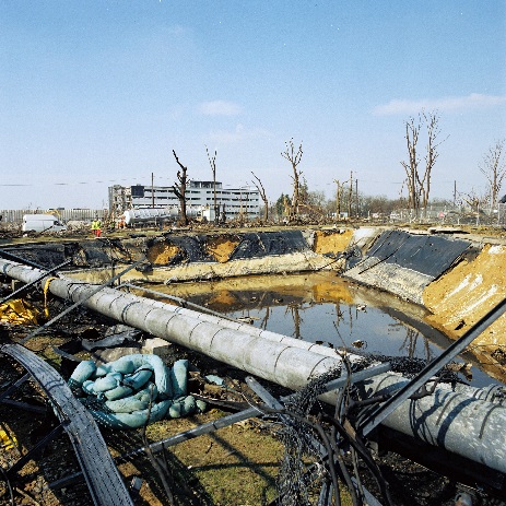 Damage to a lagoon liner with dead trees in the background