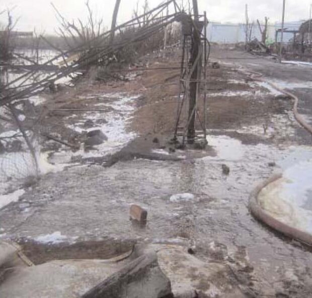 Runoff from the site boundary into road with dead trees in the background. 
