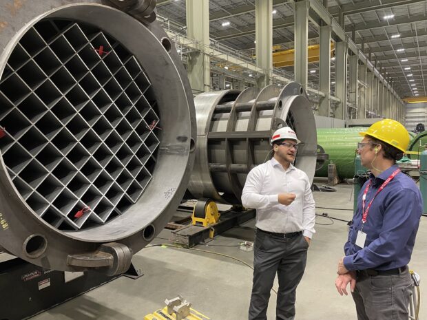 Two men discuss production of components at a manufacturing facility.