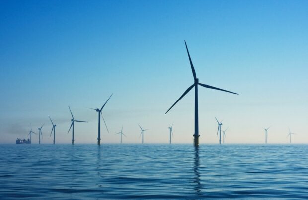 Photo of offshore wind turbines towering above the blue sea off the Sussex Coast.