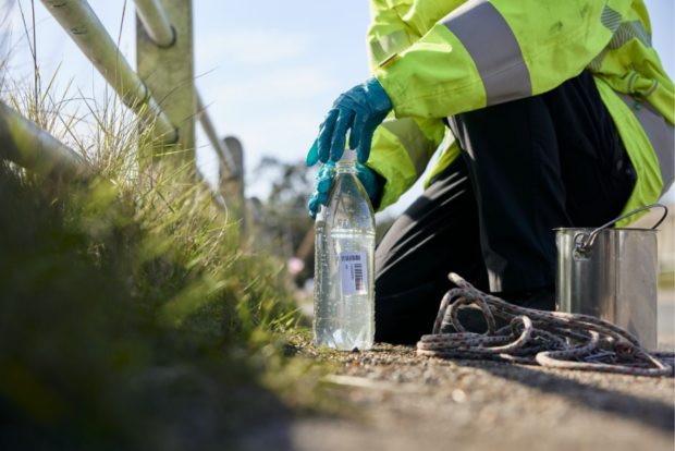 An officer kneels next to a sample bottle.