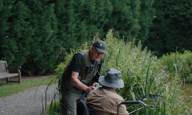 A Fisheries Enforcement Officer speaks to an angler to check their licence. 