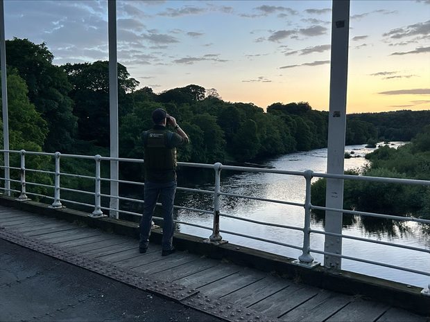  An Environment Agency officer looks out over a bridge at sunset.
