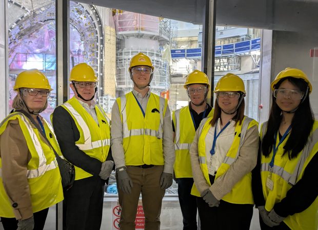 Fusion team stand infront of a fusion machine at the ITER project, France.