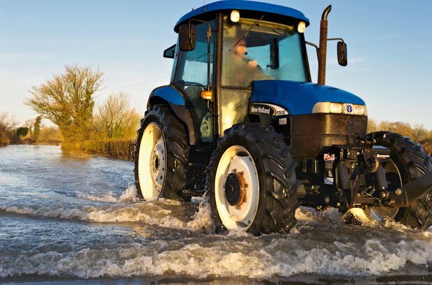 A tractor drives on a flooded road