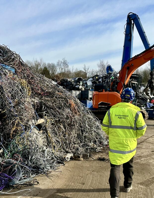 Environment Agency staff member undertaking a waste site inspection with waste and machinery