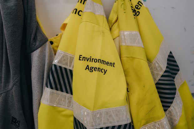 Yellow Environment Agency hi-vis jackets that have been hung up.  